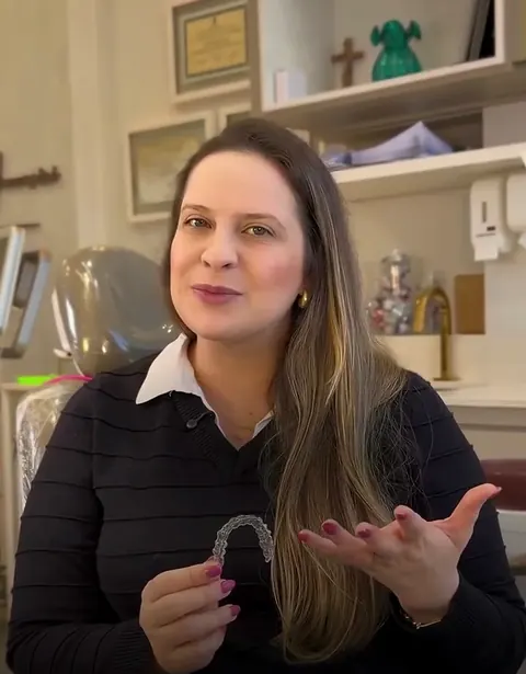 Dra. Gabriella mostrando um alinhador transparente no consultório